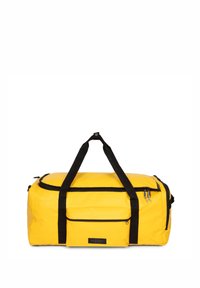 Bolso de deporte amarillo fabricado con un material liso y duradero. Cuenta con correas negras, un bolsillo frontal con cremallera y un cierre superior con cremallera.
