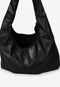 Bolso hobo de cuero negro suave con un diseño relajado, gran abertura y bolsillo interior con cremallera. Acabado con una textura mate y suave.