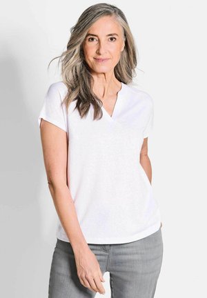 White short-sleeve V-neck shirt, soft texture, relaxed fit, paired with light gray jeans. Plain design, no visible patterns or accents.