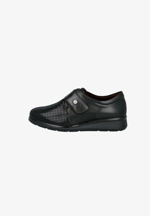 Zapato negro de cuero sin cordones con parte delantera texturizada, correa ajustable de Velcro y suela acolchada diseñada para comodidad y facilidad de uso.