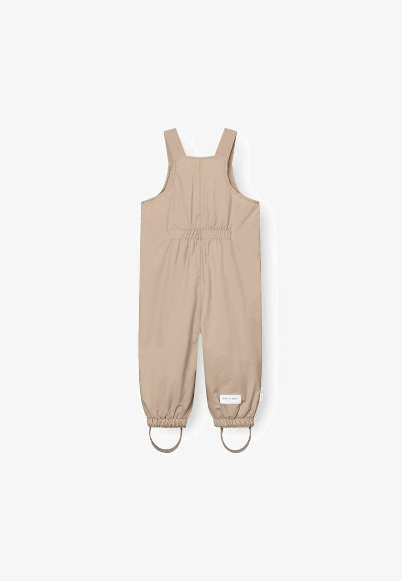 Salopette beige, impermeabile, con bretelle regolabili, polsini elasticizzati e due dettagli circolari in metallo sulle gambe; texture liscia.