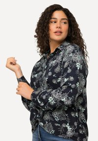 Blusa marina con stampa floreale bianca e menta, design con bottoni, maniche lunghe e tessuto testurizzato; orlo curvo e dettagli del colletto.