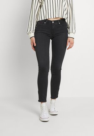 Jeans negros ajustados con una cintura de medio talle, con un detalle de cremallera en los tobillos y una textura de tela suave.