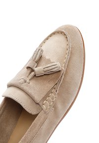 Mocassino in suede beige con punta rotonda, nappine decorative e dettagli di cucitura lungo i bordi. Fodera interna in pelle liscia.
