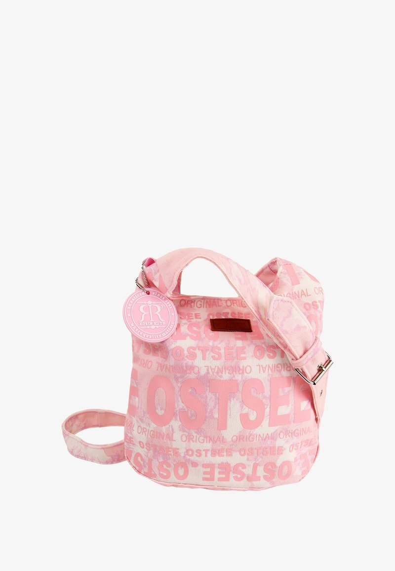 Rosa Canvas-Tasche mit großem "OSTSEE"-Schriftzug, verstellbarem Riemen und einem runden Anhänger mit Logo. Glatte Textur, lässiges Design.
