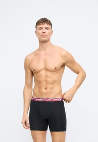 Čierne pánske boxerky s farebným kamuflážovým pásom, na ktorom je logo Nike, vyrobené z pružného materiálu pre pohodlie a dobré priliehanie.