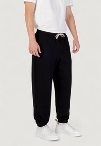 Zwarte joggingbroek met een elastische tailleband, een trekkoord en zijzakken. Gemaakt van zacht materiaal met een licht toelopend ontwerp van de pijpen.