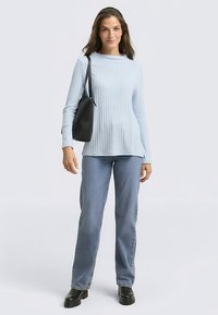 Jasnoniebieski prążkowany top z długim rękawem, luźny krój, zestawiony z prostymi niebieskimi dżinsami i czarnymi botkami za kostkę, czarna torba na ramię.
