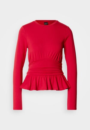 Červený dlhý rukáv s okrúhlym výstrihom, zdobený detailmi pri páse a rozšíreným peplum lemom z jemnej, pružnej tkaniny.