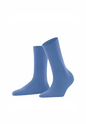Ein Paar schlichte, hellblaue Kniestrümpfe, stehen aufrecht, wobei ein Strumpf leicht nach vorne geneigt ist, vor weißem Hintergrund.