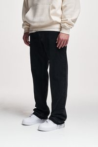 Blugi negri din denim cu un croi drept, asortați cu un hanorac crem cu glugă și adidași albi. Materialul pare robust și texturat.