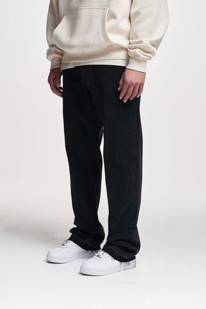 Jean en denim noir avec une coupe droite, associé à un sweat à capuche crème et des baskets blanches. Le tissu semble solide et texturé.