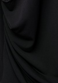 Tissu noir avec une texture drapée, présentant des plis doux et une surface lisse. Légèrement réfléchissant, suggérant un matériau léger et respirant.