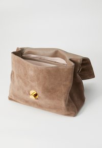 Suede handbag in light brown with a textured finish. Features a round gold magnetic snap closure and an open top design. Interior is lined.