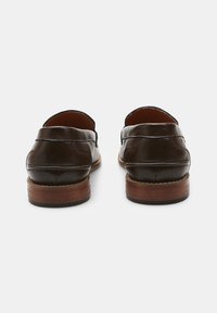 Barna bőr loaferek sima textúrával, varrott részletekkel és fa sarokkal. A design jellemzői között szerepel a kerek orr és a slip-on stílus.