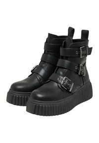 Botines negros de cuero con múltiples correas ajustables y acentos de hebilla. Suela de goma gruesa y estriada.