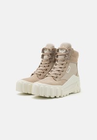 Beige hoge sneakers met een bovenwerk van suede en stof, voorzien van een dikke witte rubberen zool met opvallende ribbels en kenmerkende vetersluiting hardware.