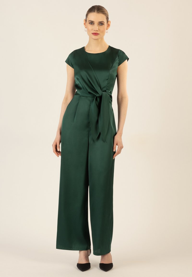 Green satin jumpsuit with cap sleeves, a fitted bodice, and a tied waist detail. Wide-leg trousers with a smooth texture and elegant drape.