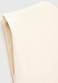 Crème-kleurige, geribbelde gebreide stof met een zachte textuur en een mouwloos ontwerp, dat een gladde, ronde halslijn en gebogen randen laat zien.