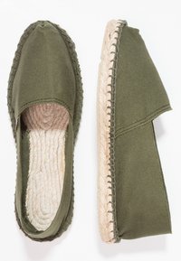 Green canvas espadrilles with a jute rope sole and stitching detail. Open back design with textured interior lining.