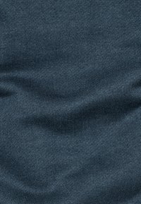 Mörkblått stickat tyg med fina, jämna ribbor och subtila veck som skapar en mjuk textur och subtila skuggor.