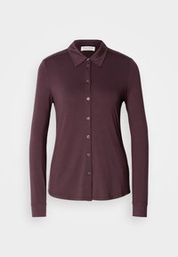 Chemise à manches longues boutonnée de couleur prune foncée avec un col pointu, présentée sur un fond clair uni.