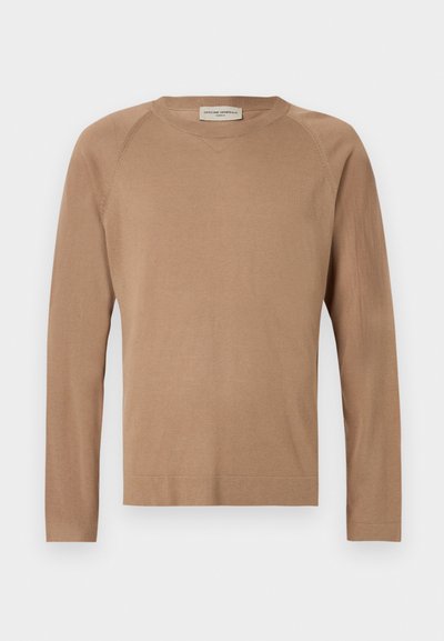 Világosbarna kötött pulóver hosszú ujjakkal, kerek nyakkivágással és raglan varrásokkal. Puha tapintású és egyszerű dizájnú. Díszítések nélküli és sokoldalú.