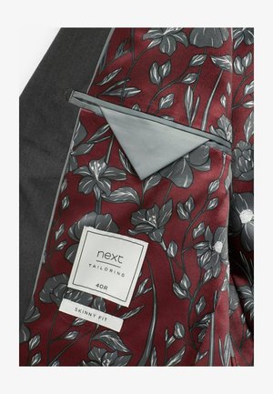 Interno di giacca su misura borgogna con motivo floreale grigio e una texture liscia. L'etichetta riporta "next Tailoring 40R Skinny Fit."