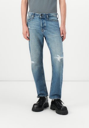 Jeans in denim azzurro sbiadito con vestibilità dritta, caratterizzati da toppe sfilacciate sulle ginocchia e un classico design a cinque tasche.