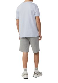 Lichtblauwe katoenen T-shirt met een ronde hals, gecombineerd met grijze katoenen shorts. Gekozen met witte sneakers en gestreepte sokken.