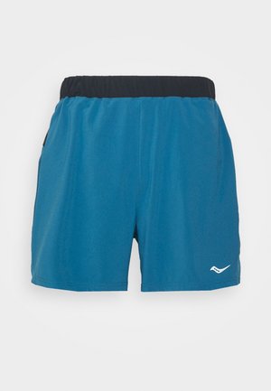 Blå idrottsshorts med ett elastiskt svart midjeband. Tillverkade av slät tyg, med en vit logotyp på nedre högra sidan. Inga fickor synliga.