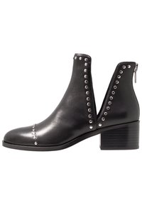 Black leather ankle boots with metal stud detailing, cut-out sides, and a chunky heel. Features a zipper at the back for easy wear.