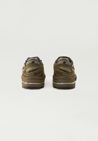 Brown New Balance 1000 sneakers featuring a textured suede upper, dark grey accents, and a cushioning midsole with reflective detail.