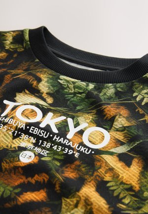 Čierna mikina so vzorom zelených a hnedých listov. Obsahuje biely text "TOKYO" a súradnice. Rebrovaný čierny výstrih.