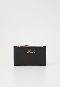 Black cardholder made of smooth leather, featuring a gold zipper and embossed signature. Rectangular shape with minimalistic design.