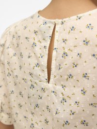 Floral blouse in lightweight fabric with white base, small blue flowers, and green accents. Features a keyhole back and button closure.
