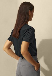Dark blue short-sleeve t-shirt made of cotton, paired with gray tailored trousers featuring a back pocket. Simple and minimal design.