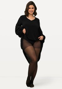 Top nero a maniche lunghe con maniche voluminose, abbinato a delle collant nere in rete trasparente. L'outfit presenta una scollatura a V e una vestibilità rilassata.