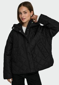Czarna pikowana kurtka z kapturem, zapinana na zatrzaski, o teksturowanej powierzchni. Posiada przednią kieszeń i luźny krój.
