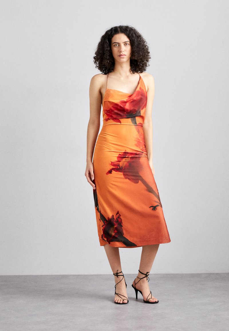 Rochie satinată portocalie cu imprimeu floral, siluetă ajustată, decolteu asimetric și bretele subțiri. Se asortează cu sandale negre cu bretele.