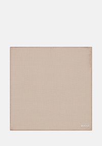 Kvadratinis padėkliukas šviesiai beige spalvos, tekstūruota paviršius su subtiliu raštu, siuvinėta kraštinė ir logotipas dešiniajame apatiniajame kampe.