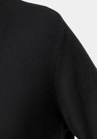 Schwarzes Strickoberteil mit glatter Textur, klassischem Rundhalsausschnitt und angeschnittenen Ärmeln. Sichtbares Steppdetail an den Schultern.