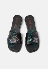 Black slide sandals featuring floral embroidery in pink, blue, and green. Smooth leather upper and rubber sole. Textured footbed for comfort.
