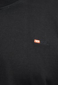 Μαύρο βαμβακερό φούτερ με στρογγυλή λαιμόκοψη. Διαθέτει μικρό πορτοκαλί και κόκκινο κεντητό λογότυπο "DIESEL" στο στήθος. Με λεία υφή.