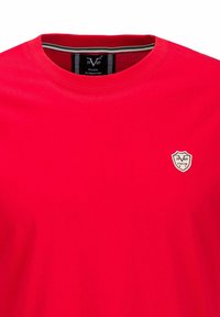 Rode katoenen T-shirt met een ronde halslijn en korte mouwen. Heeft een klein embleem op de linkerborst met de tekst "1969" en "ITALIA".