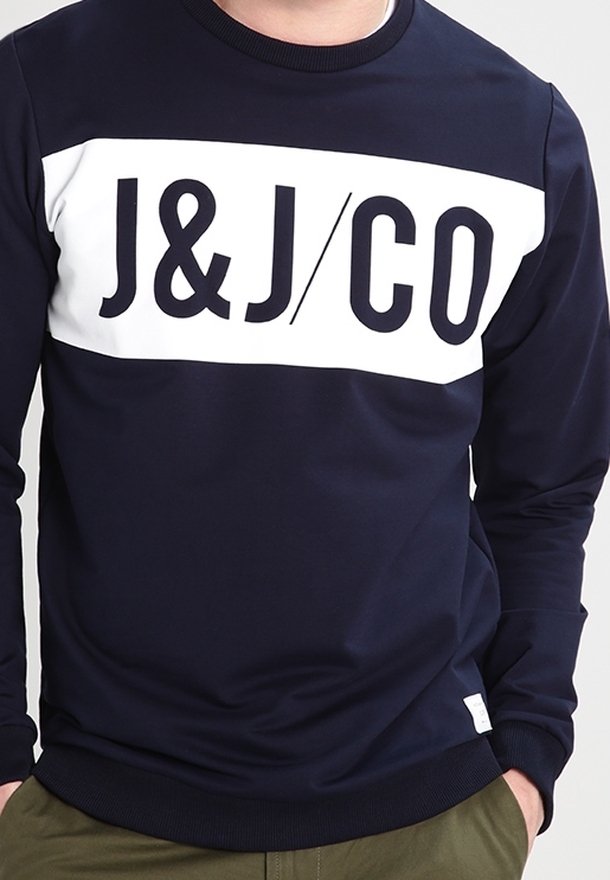 Mörkblå sweatshirt med en vit horisontell rand som har "J&J/CO" logotypen i fet svarta bokstäver. Ribbad halsringning och muddar, mjuk textur.