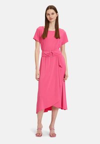 Rosa knielanges Kleid aus weichem Stoff, mit kurzen Ärmeln, einer taillierten Taille mit einer runden Schnalle und einem asymmetrischen Saum.