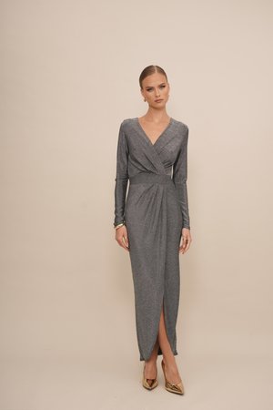 Robe longue argentée avec décolleté en V, manches longues et fente sur le côté, présentant une taille cintrée et un design drapé. Associée à des talons dorés.