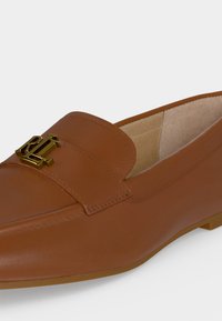 Καφέ δερμάτινο loafer με χρυσό μεταλλικό λογότυπο RL στο πάνω μέρος και χαμηλό τακούνι, με λεία επιφάνεια και ραμμένες λεπτομέρειες.