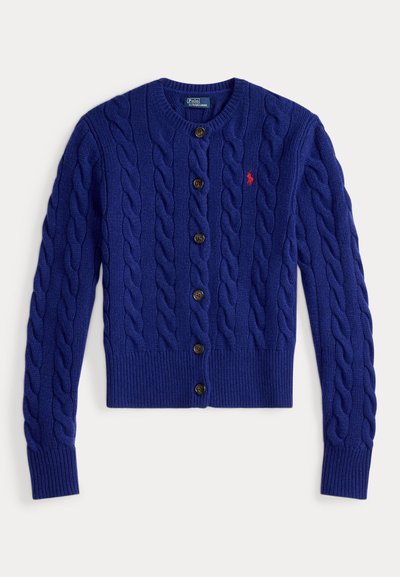 Blå strikket cardigan med kabelflettemønster, rund halslinning og fem mørke knapper. Har liten rød logo på venstre bryst.